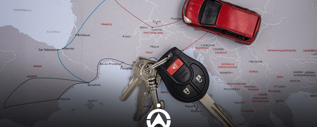 A red toy car and a set of keys placed on a map of Europe, highlighting travel routes in France, Spain, and beyond.